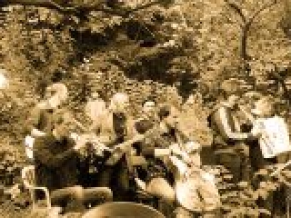 Foto in Sepia: Orchester spielt auf einer von B&auml;umen mit viel Bl&auml;ttern umwachsenen Terrasse