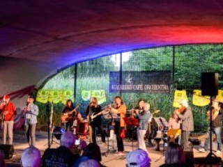 Foto: kleines Orchester spielt unter einem bunt beleuchteten Br&uuml;ckenbogen