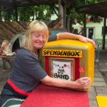 Foto: Frau umklammert einen Briefkasten der zur Spendenbox umfunktioniert wurde